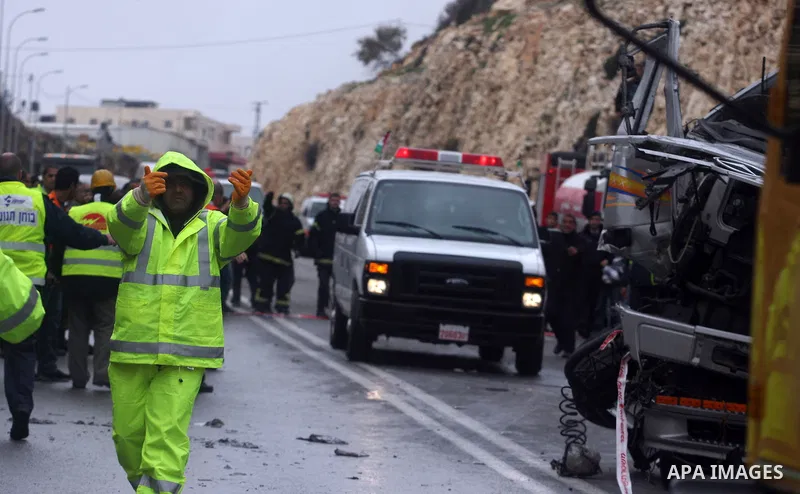 Israeli and Palestinian rescue workers stand with onlookers at the scene of an accident near the Qalandiya checkpoint outside the West Bank city of Ramallah February 16, 2012. At least five Palestinian children were kill...