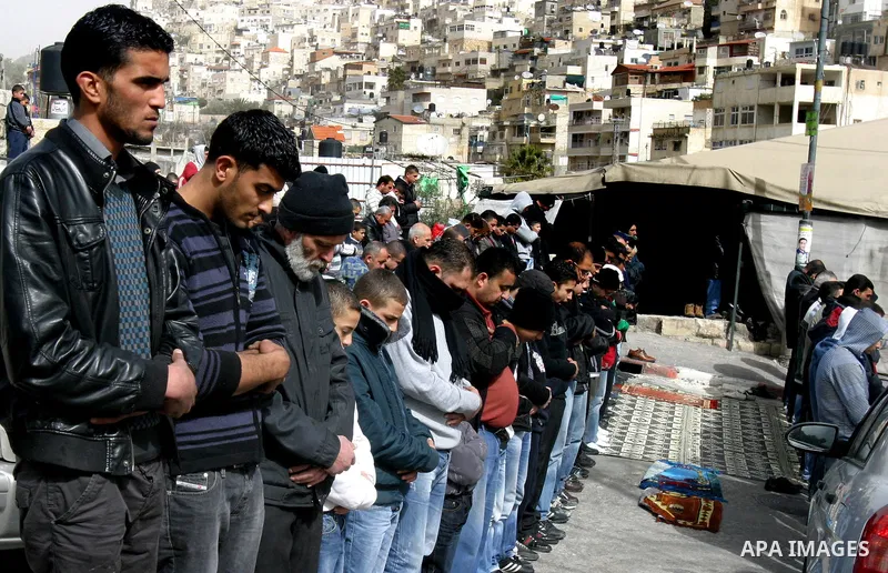 Palestinians pray on a street outside a protest tent during Friday noon prayers on 17 Feb 2012 in the Silwan neighborhood of East Jerusalem. Silwan is seen behind.. Photo by Mahfouz Abu Turk
