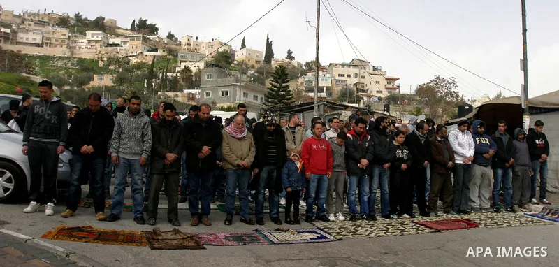 Palestinians pray on a street outside a protest tent during Friday noon prayers on 17 Feb 2012 in the Silwan neighborhood of East Jerusalem. Silwan is seen behind.. Photo by Mahfouz Abu Turk