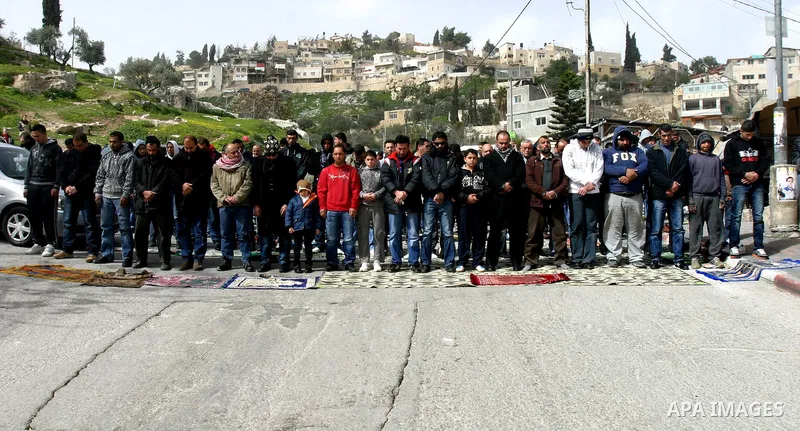 Palestinians pray on a street outside a protest tent during Friday noon prayers on 17 Feb 2012 in the Silwan neighborhood of East Jerusalem. Silwan is seen behind.. Photo by Mahfouz Abu Turk