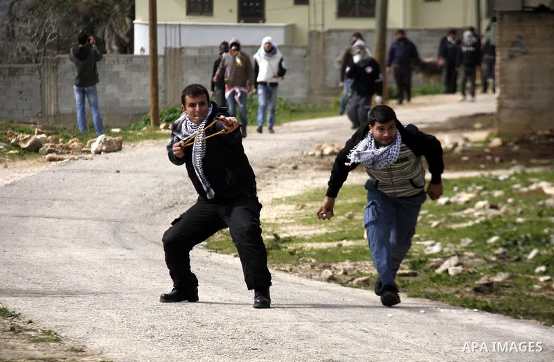 Palestinian youths hurl stones at Israeli troops during a protest in the village of Kufr Qaddum against the expansion of the nearby Jewish settlement of Kdumim, in the northern West Bank, Friday, Feb. 17, 2012. Photo by...