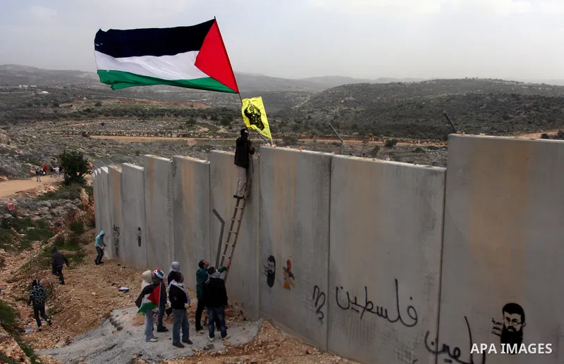 A protestor waves a Palestinian flag in front of Israeli troops during a protest against Israel's separation barrier in the West Bank village of Bilin, near Ramallah, Friday, Feb. 17, 2012. Friday's demonstration marked...