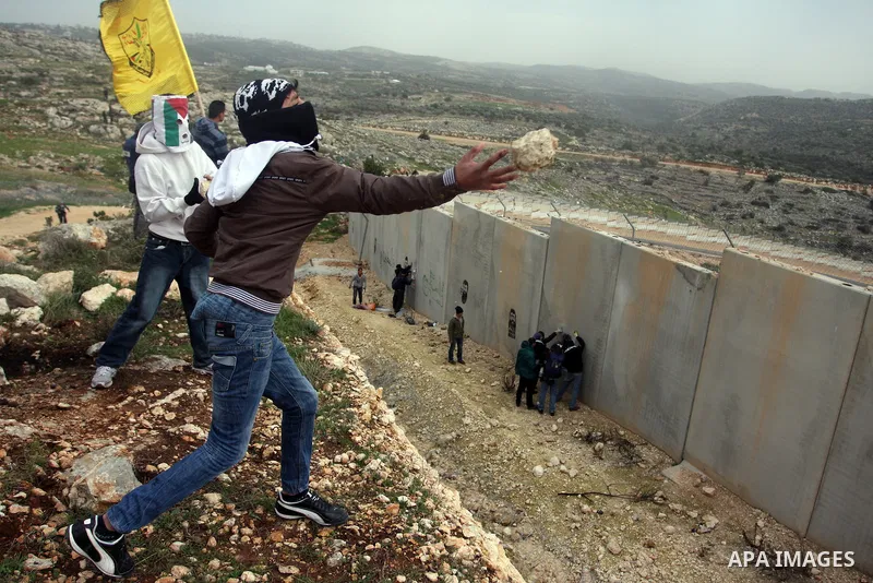 Palestinian throw stones at Israeli soldiers (not pictured) during a protest in the West Bank village of Billin, next to the Israeli settlement of Kereat Sefir, 17 February 2012, during a protest calling for the release...