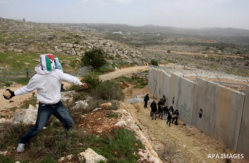 Palestinian throw stones at Israeli soldiers (not pictured) during a protest in the West Bank village of Billin, next to the Israeli settlement of Kereat Sefir, 17 February 2012, during a protest calling for the release...