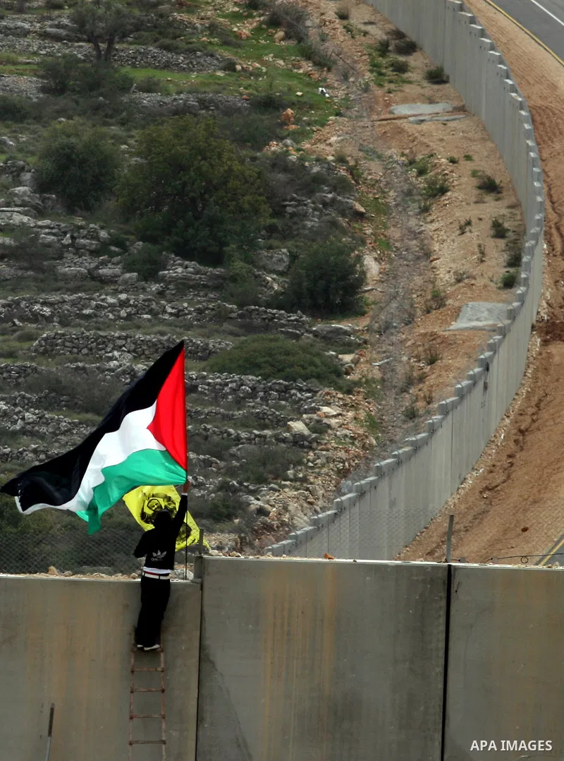A protestor waves a Palestinian flag in front of Israeli troops during a protest against Israel's separation barrier in the West Bank village of Bilin, near Ramallah, Friday, Feb. 17, 2012. Friday's demonstration marked...