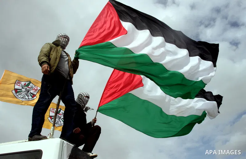 Palestinian activists hold Palestinian national flags in front of the separation barrier during a protest in the West Bank village of Billin, next to the Israeli settlement of Kereat Sefir, 17 February 2012, during a pro...