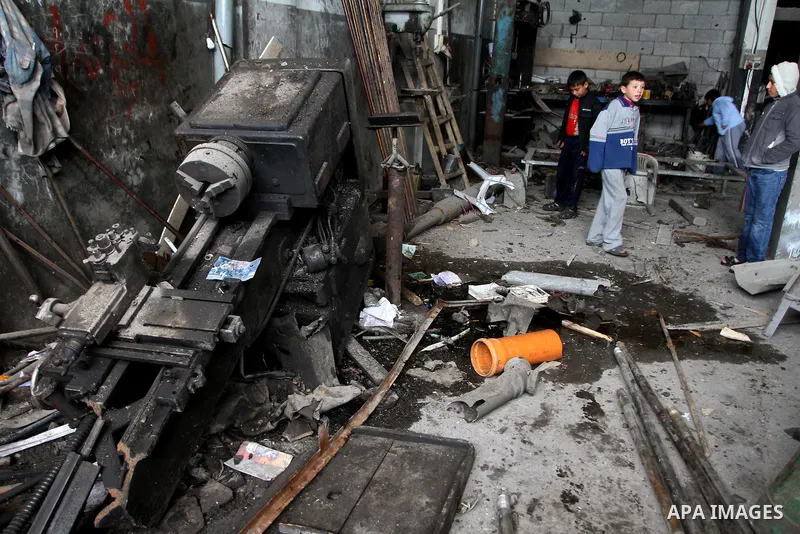 Palestinians look at what they said is a metal workshop which was damaged in an Israeli air strike on Saturday night in Gaza City February 19, 2012. Photo by Ashraf Amra