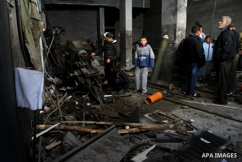 Palestinians look at what they said is a metal workshop which was damaged in an Israeli air strike on Saturday night in Gaza City February 19, 2012. Photo by Ashraf Amra
