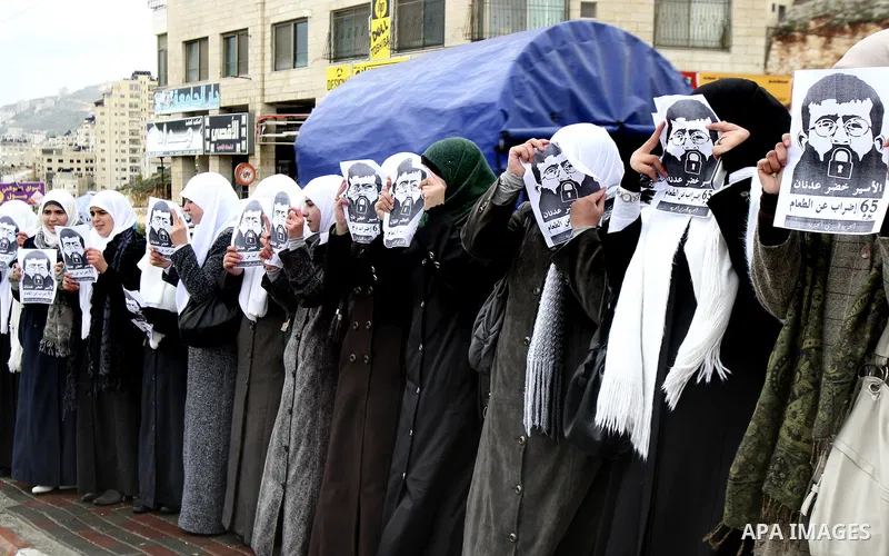 Palestinian women hold posters with the image of Khader Adnan, a senior member of Islamic Jihad jailed in Israel who has been on hunger strike for 64 days, during a protest calling for the release of Adnan and other Pale...