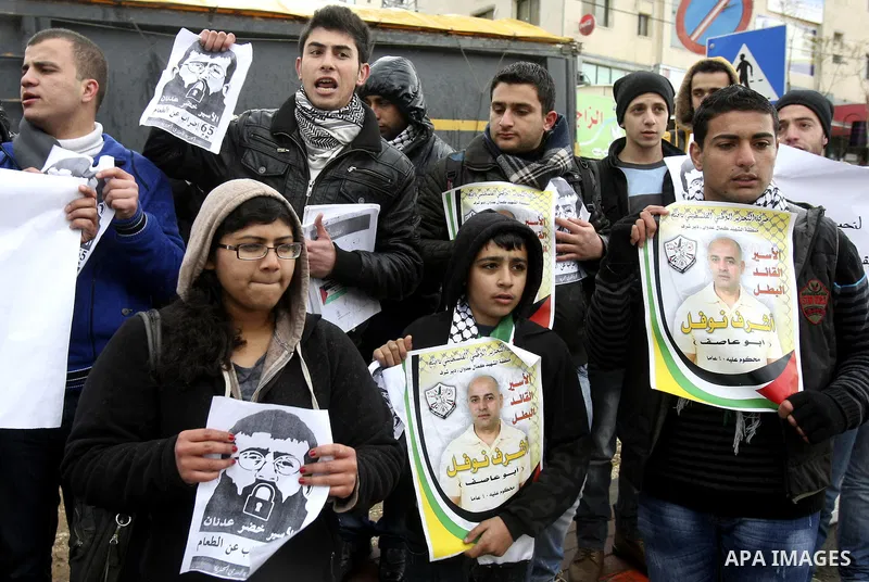 Palestinian women hold posters with the image of Khader Adnan, a senior member of Islamic Jihad jailed in Israel who has been on hunger strike for 64 days, during a protest calling for the release of Adnan and other Pale...