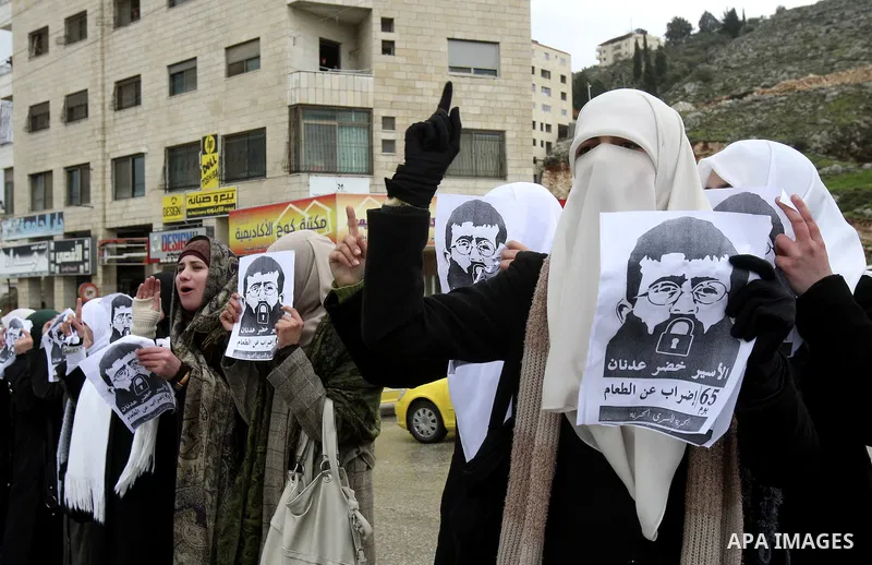 Palestinian women hold posters with the image of Khader Adnan, a senior member of Islamic Jihad jailed in Israel who has been on hunger strike for 64 days, during a protest calling for the release of Adnan and other Pale...