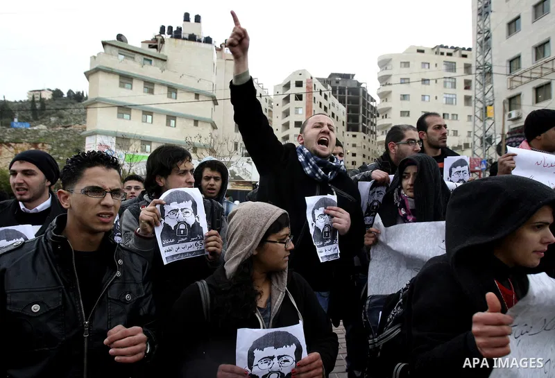 Palestinian women hold posters with the image of Khader Adnan, a senior member of Islamic Jihad jailed in Israel who has been on hunger strike for 64 days, during a protest calling for the release of Adnan and other Pale...