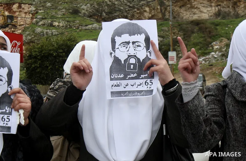 Palestinian women hold posters with the image of Khader Adnan, a senior member of Islamic Jihad jailed in Israel who has been on hunger strike for 64 days, during a protest calling for the release of Adnan and other Pale...