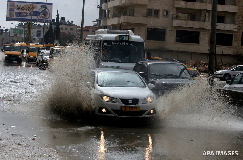Palestinians walk in a street during the heavy rain of the winter, in west bank City of Ramallah, Feb. 19, 2012. Photo by Issam Rimawi