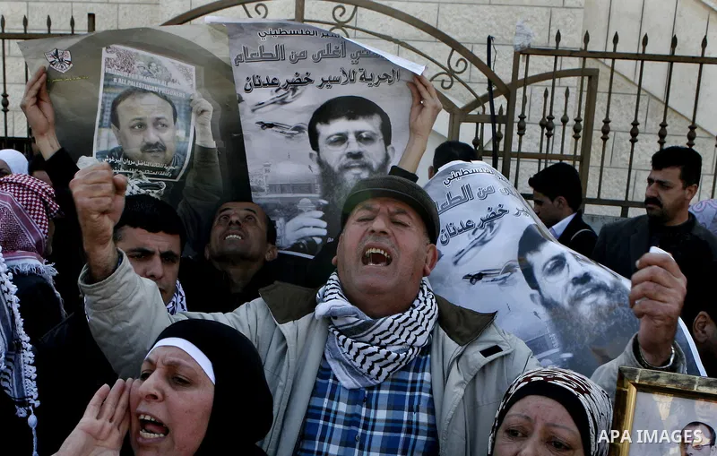 Palestinians hold posters with the image of Khader Adnan, a senior member of Islamic Jihad jailed in Israel who has been on hunger strike for 65 days, during a protest calling for the release of Adnan and other Palestini...