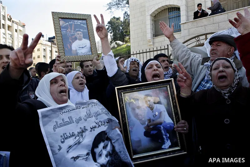 Palestinians hold posters with the image of Khader Adnan, a senior member of Islamic Jihad jailed in Israel who has been on hunger strike for 65 days, during a protest calling for the release of Adnan and other Palestini...