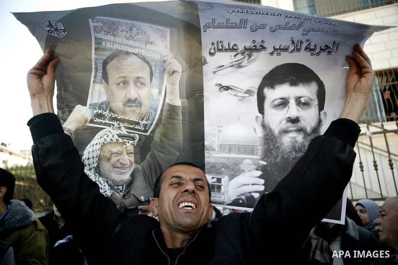 Palestinians hold posters with the image of Khader Adnan, a senior member of Islamic Jihad jailed in Israel who has been on hunger strike for 65 days, during a protest calling for the release of Adnan and other Palestini...