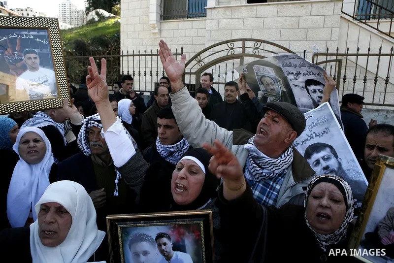 Palestinians hold posters with the image of Khader Adnan, a senior member of Islamic Jihad jailed in Israel who has been on hunger strike for 65 days, during a protest calling for the release of Adnan and other Palestini...