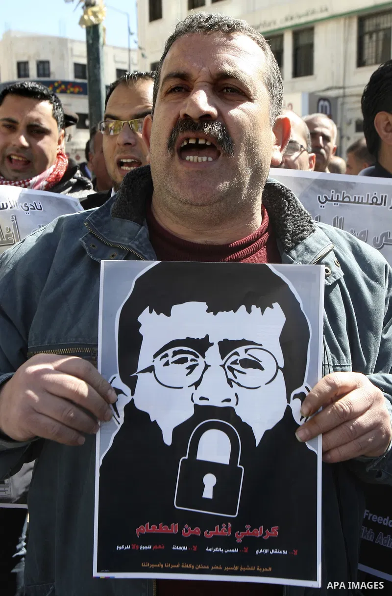A Palestinian protestor holds a picture of Khader Adnan, 33, a senior member of Islamic Jihad jailed in Israel, during a demonstration in solidarity with Adnan, in the West Bank city of Nablus, on February 21, 2012, shor...