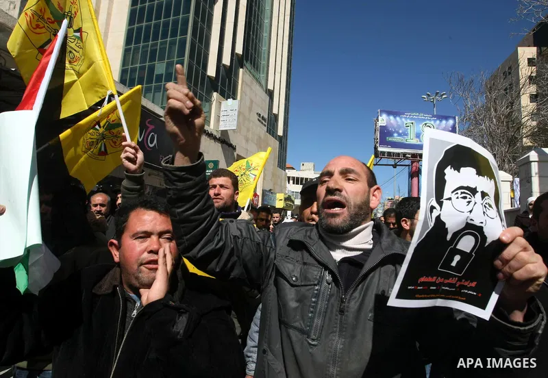 Palestinians holds a picture of Khader Adnan, a senior member of Islamic Jihad jailed in Israel, who has been on hunger strike for 66 days, during a protest calling for the release of Adnan and other Palestinians, in the...