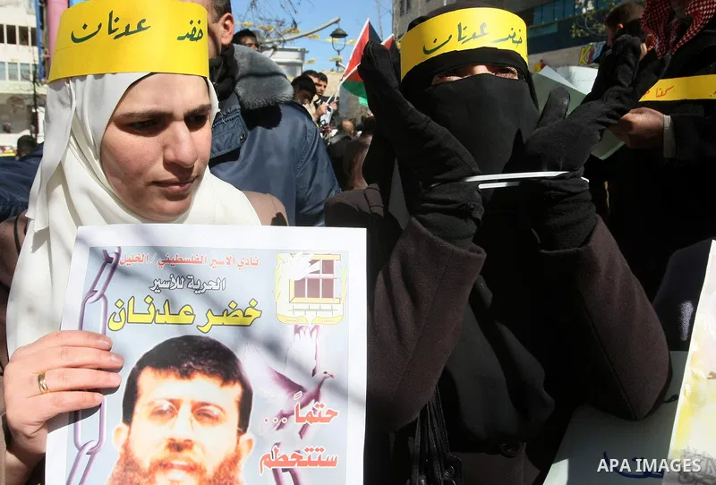 Palestinians holds a picture of Khader Adnan, a senior member of Islamic Jihad jailed in Israel, who has been on hunger strike for 66 days, during a protest calling for the release of Adnan and other Palestinians, in the...