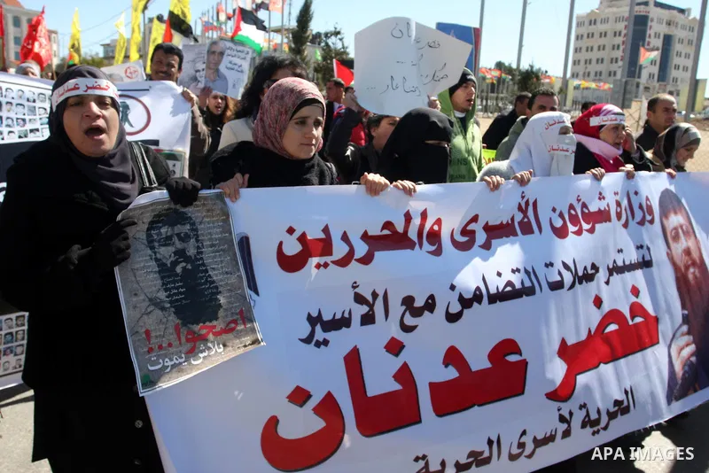 Palestinians hold a banner with an image of Islamic Jihad member Khader Adnan during a protest in his support in the West Bank city of Ramallah February 21, 2012. Adnan, held without trial by Israel, agreed on Tuesday to...