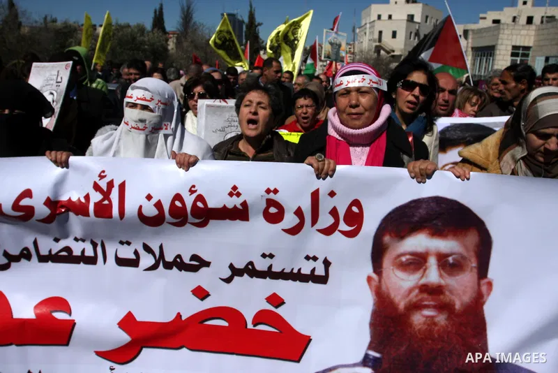 Palestinians hold a banner with an image of Islamic Jihad member Khader Adnan during a protest in his support in the West Bank city of Ramallah February 21, 2012. Adnan, held without trial by Israel, agreed on Tuesday to...