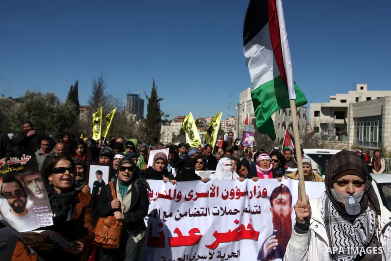 Palestinians hold a banner with an image of Islamic Jihad member Khader Adnan during a protest in his support in the West Bank city of Ramallah February 21, 2012. Adnan, held without trial by Israel, agreed on Tuesday to...