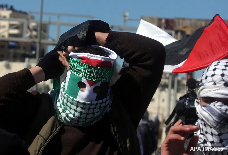 A masked protestor throws a stone towards Israeli troops during clashes outside Ofer prison near the West Bank city of Ramallah February 21, 2012. The clashes broke out after a protest in support of Islamic Jihad member...
