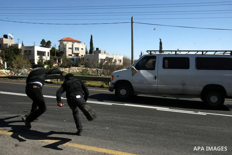 Palestinian youth throw stones at a vehicle driven by an Israeli settler along Route 60 to a Jewish settlement which passes close to the village of Beit Omar in the Israeli occupied West Bank, on February 21, 2012. Stone...