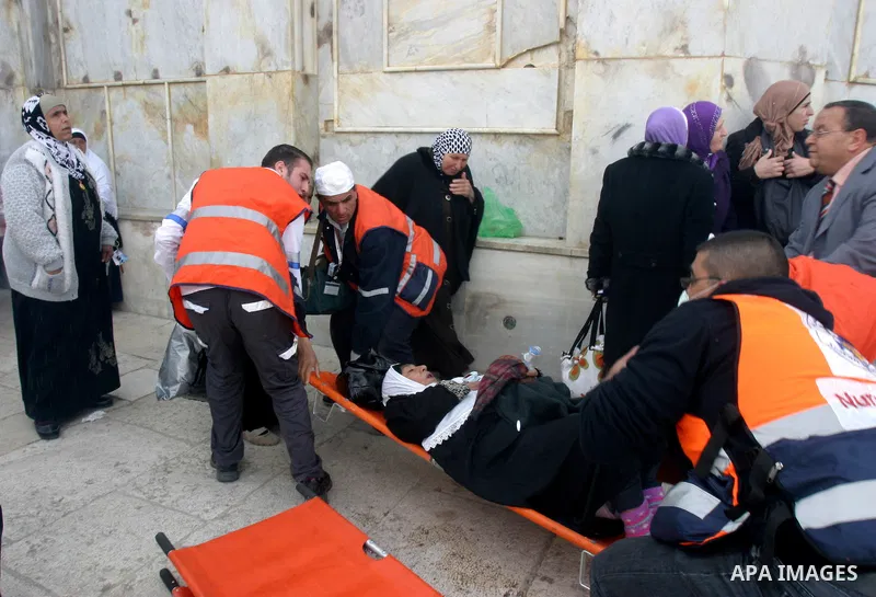 Palestinian medics hold a Palestinian woman as they remove her from near the Dome of the Rock, behind, during running clashes between Palestinians and Israeli policemen on the compound known to Muslims as the Noble Sanct...
