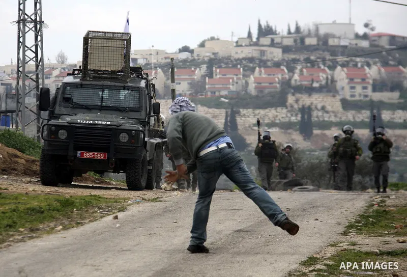 A Palestinian protester throws stones at Israeli soldiers during a demonstration against the expropriation of Palestinian land by Israel in the village of Kfar Qaddum, near the West Bank city of Nablus, on February 24, 2...