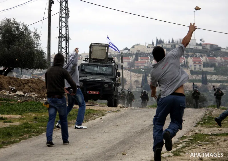 A Palestinian protester throws stones at Israeli soldiers during a demonstration against the expropriation of Palestinian land by Israel in the village of Kfar Qaddum, near the West Bank city of Nablus, on February 24, 2...