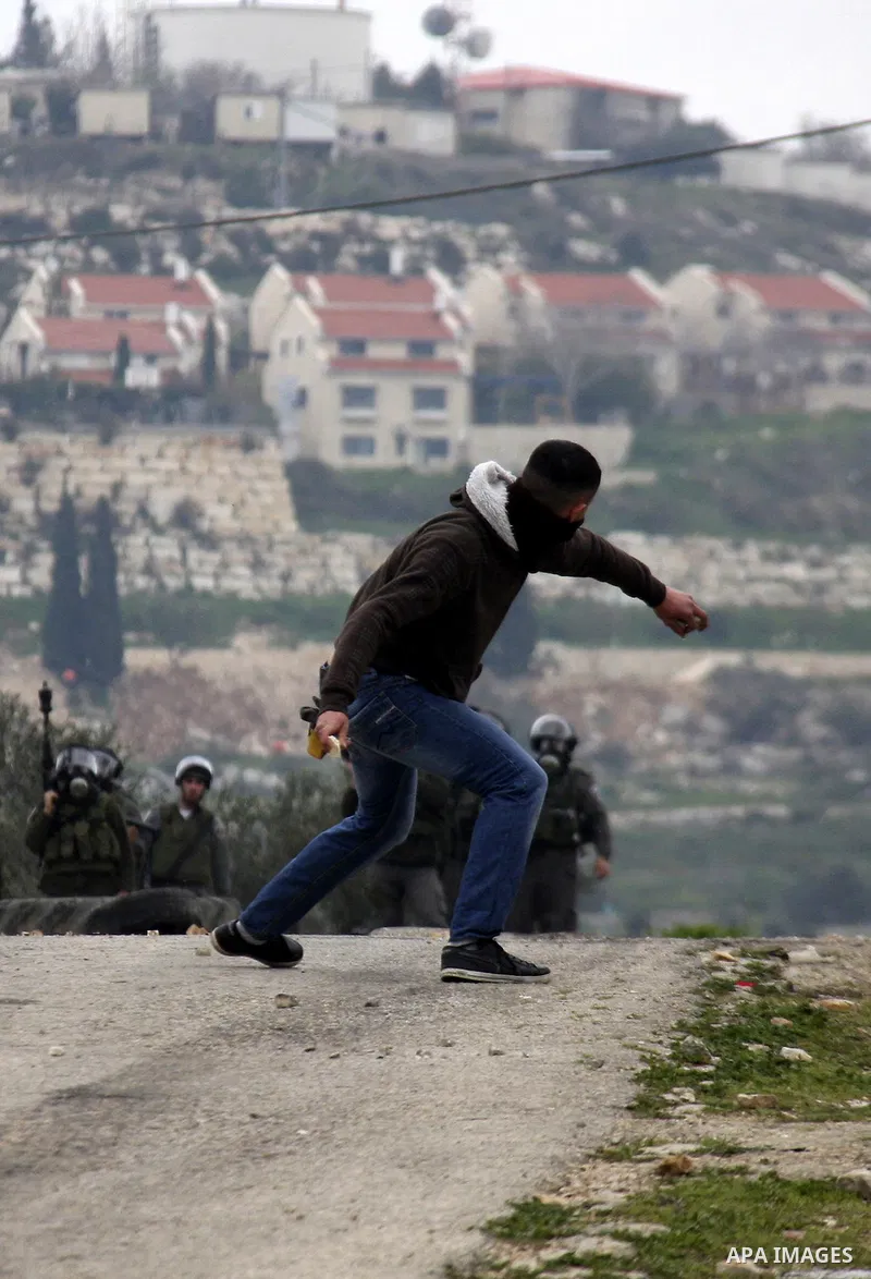 A Palestinian protester throws stones at Israeli soldiers during a demonstration against the expropriation of Palestinian land by Israel in the village of Kfar Qaddum, near the West Bank city of Nablus, on February 24, 2...