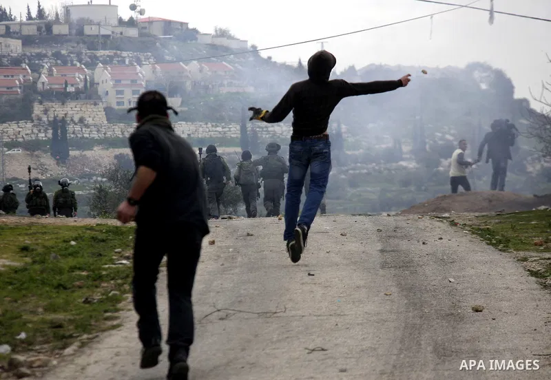 A Palestinian protester throws stones at Israeli soldiers during a demonstration against the expropriation of Palestinian land by Israel in the village of Kfar Qaddum, near the West Bank city of Nablus, on February 24, 2...