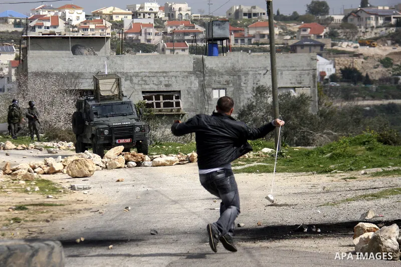 A Palestinian protester throws stones at Israeli soldiers during a demonstration against the expropriation of Palestinian land by Israel in the village of Kfar Qaddum, near the West Bank city of Nablus, on February 24, 2...