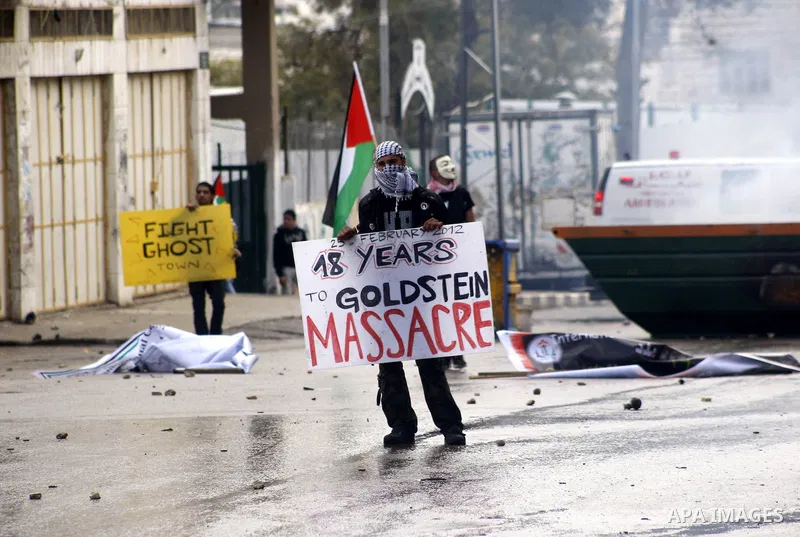 A Palestinian protester holds a placard during a demonstration against the closure of Shuhada street to Palestinians, in the West Bank city of Hebron February 24, 2012. Some 200 protesters, including foreign and Israeli...