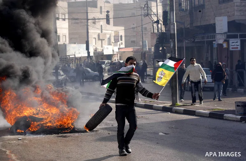 A Palestinian protester holds his national flag and a tyre during a demonstration against the closure of Shuhada street to Palestinians, in the West Bank city of Hebron February 24, 2012. Some 200 protesters, including f...