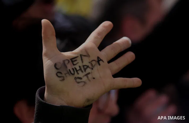 A Palestinian protester holds a placard during a protest against the closure of Shuhada street to Palestinians, in the West Bank city of Hebron February 24, 2012. Some 200 protesters, including foreign and Israeli activi...