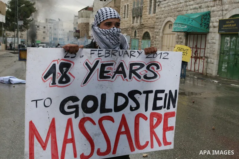 A Palestinian protester holds a placard during a protest against the closure of Shuhada street to Palestinians, in the West Bank city of Hebron February 24, 2012. Some 200 protesters, including foreign and Israeli activi...