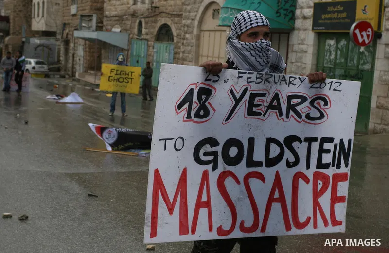 A Palestinian protester holds a placard during a protest against the closure of Shuhada street to Palestinians, in the West Bank city of Hebron February 24, 2012. Some 200 protesters, including foreign and Israeli activi...