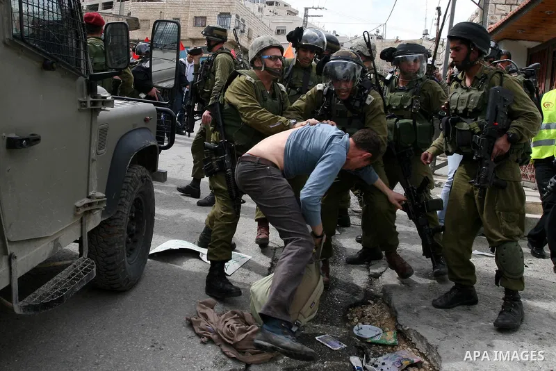 Israeli troops arrest a protester during a demonstration by Palestinians and peace activists demanding the reopening of a key street in the West Bank city of Hebron, 24 February 2012. Hundreds of Palestinians protested t...
