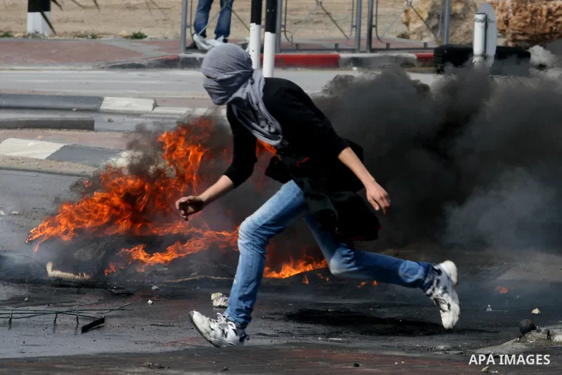 Masked Palestinian protesters run away from tear gas fired by Israeli security forces, not pictured, during clashes in the West Bank town of Al-Ram, near Jerusalem, Saturday, Feb. 25, 2012. Clashes erupted after the fune...