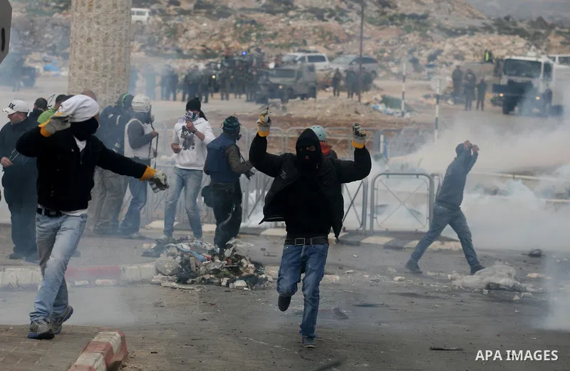 Masked Palestinian protesters run away from tear gas fired by Israeli security forces, not pictured, during clashes in the West Bank town of Al-Ram, near Jerusalem, Saturday, Feb. 25, 2012. Clashes erupted after the fune...
