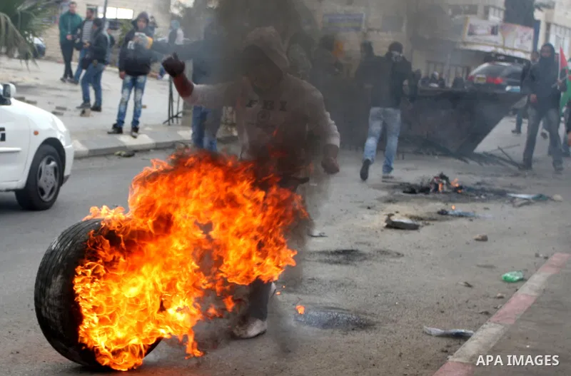 Palestinian stone throwers burn tires durign clashes with Israeli soldiers in the West Bank neighbourhood of Al-Ram, adjacent to Israeli-annexed east Jerusalem, on February 25, 2012. At least nine Palestinians were injur...