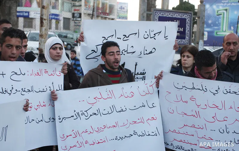Palestinians hold up banners for Hana Al-Shalabi, a Palestinian prisoner on hunger strike jailed in Israel, as they protest against Israel's policy of administrative detention, in the West Bank city of Ramallah , Monday,...