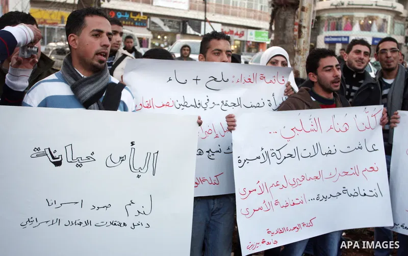 Palestinians hold up banners for Hana Al-Shalabi, a Palestinian prisoner on hunger strike jailed in Israel, as they protest against Israel's policy of administrative detention, in the West Bank city of Ramallah , Monday,...