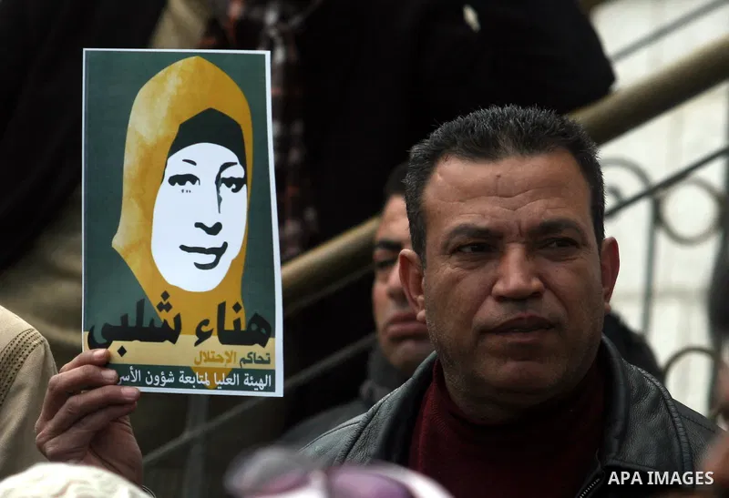 Palestinians hold a picture for Hana Al-Shalabi, a Palestinian prisoner on hunger strike jailed in Israel, as they protest against Israel's policy of administrative detention, in the West Bank city of Ramallah , Monday,...
