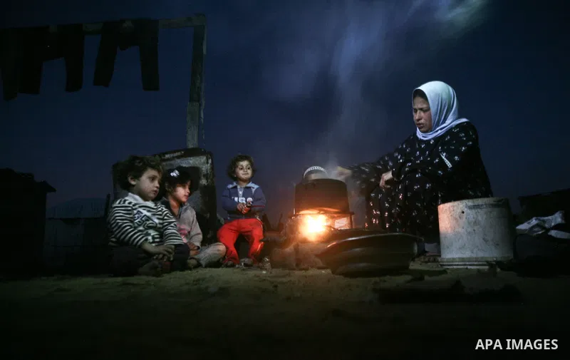 A Palestinian mother cooks on firewood at their house inbetween makeshift tents in one of the most poor regions in Al-Nusirat neighborhood, central Gaza Strip on 28 February 2012. The United Nations Relief and Works Agen...