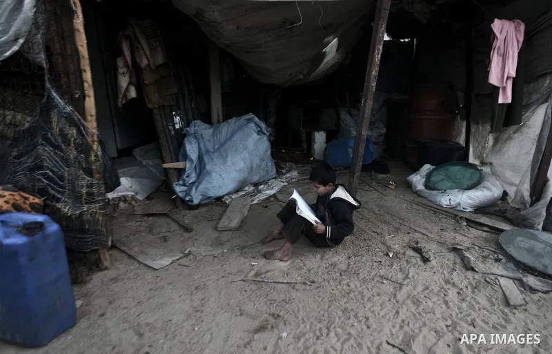 A Palestinian child is doing home work inside his family tent in one of the most poor regions in Al-Nusirat neighborhood, central Gaza Strip on 28 February 2012. The United Nations Relief and Works Agency for Palestine R...